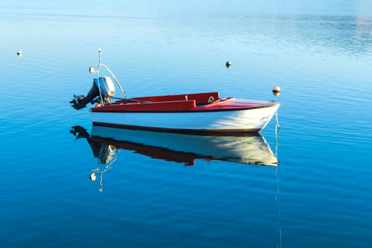 Small red and white boat at the middle of the blue water
