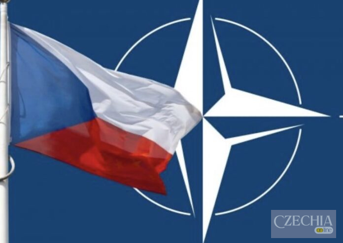 Прапор Чехії на тлі емблеми НАТО Державний прапор Чеської Республіки майорить на тлі великого логотипа Північноатлантичного альянсу. Матеріал про фінансування оборонного сектору Чехії.