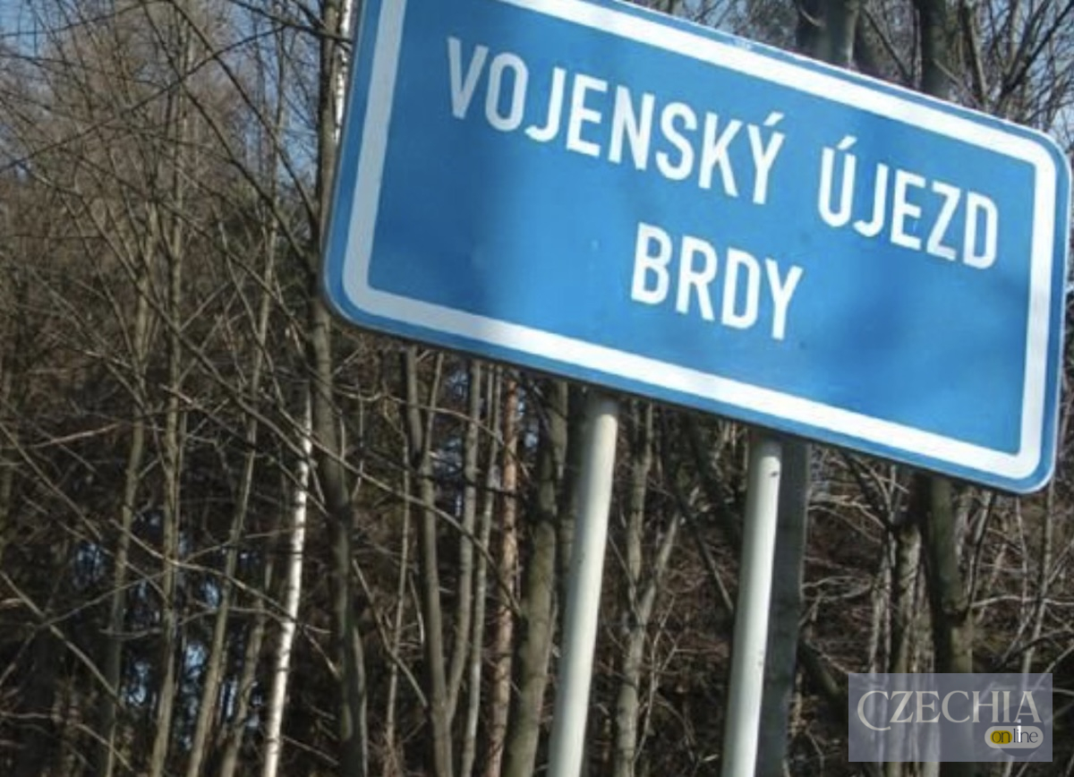 Знак військового полігону Синій дорожній знак із написом Vojenský újezd Brdy на тлі дерев.