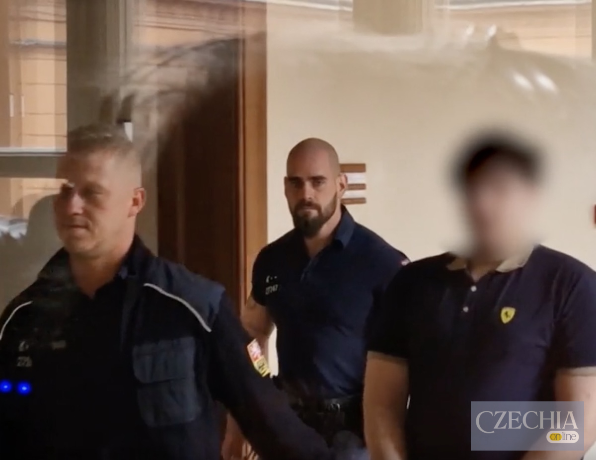 Поліцейський конвой супроводжує підозрюваного з розмитим обличчям у будівлі суду.