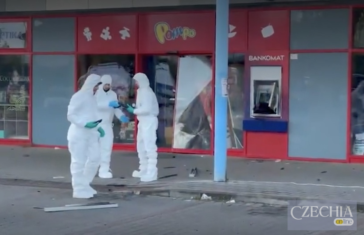 Троє поліцейських у білих захисних костюмах оглядають місце вибуху банкомата біля магазину іграшок.
