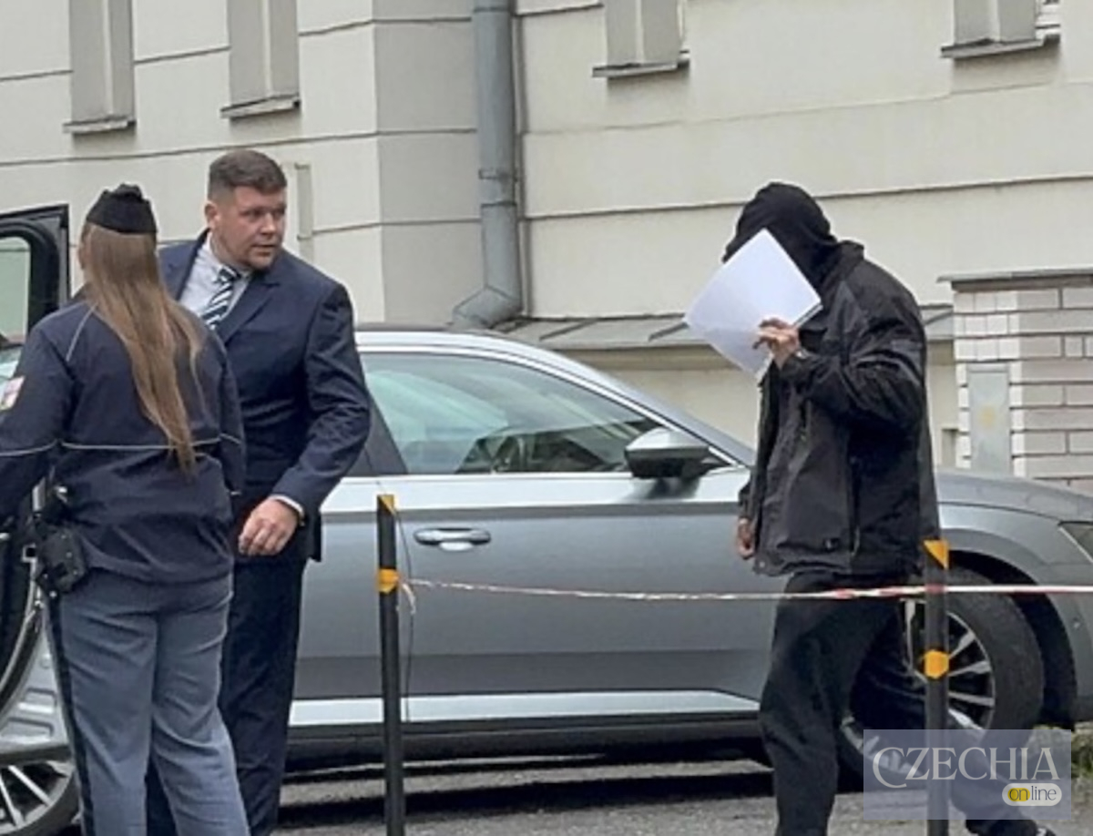 Підозрюваний у крадіжці черепа святої Здислави ховає обличчя за аркушем паперу біля будівлі суду в Чеській Липі.