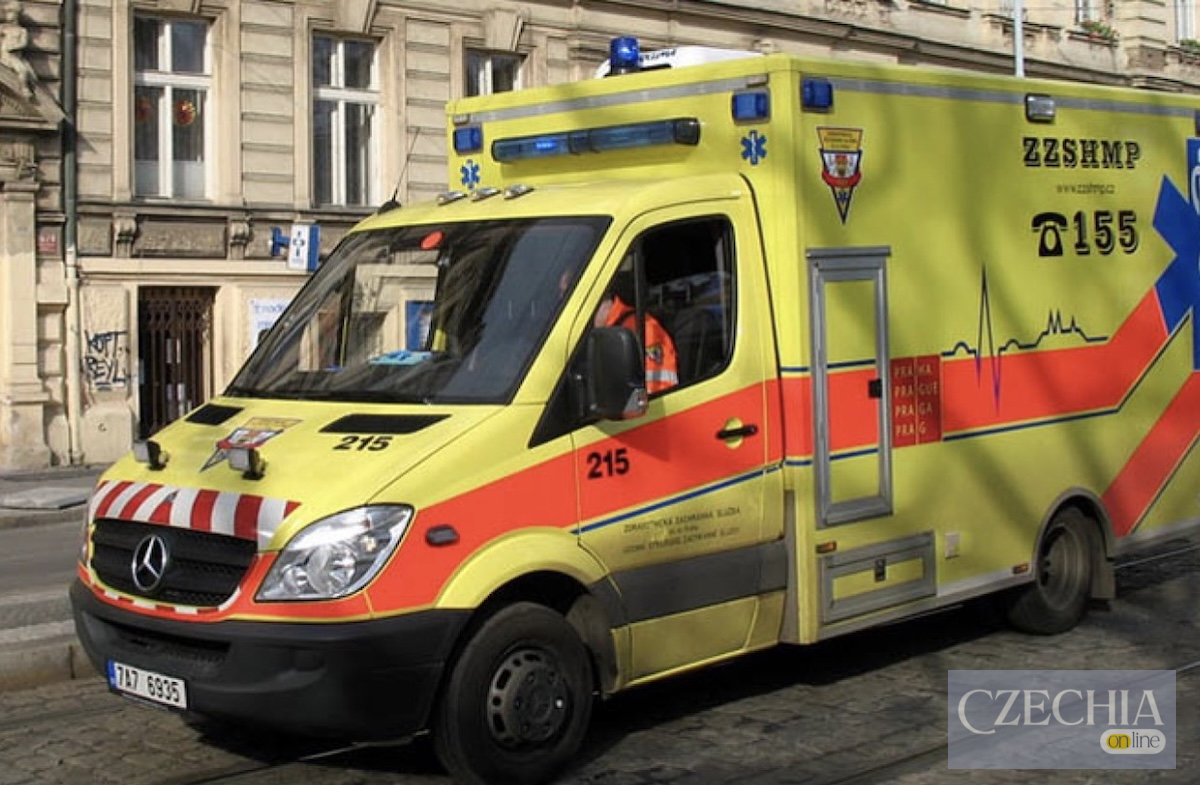 Жовтий автомобіль швидкої допомоги з червоними смугами та номером 155 їде бруківкою у Празі. Матеріал про правила виклику медиків у Чехії.