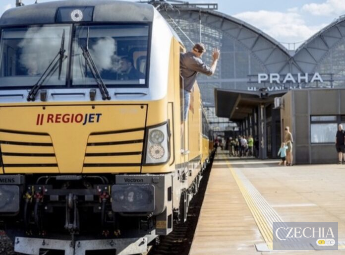 Жовтий локомотив потяга RegioJet на платформі Головного вокзалу Праги. З вікна кабіни махає рукою машиніст. Матеріал про затримку рейсу.