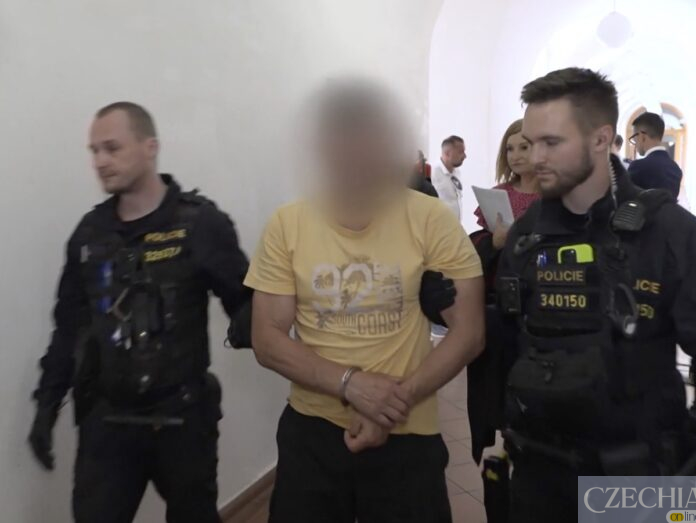 Поліцейські ведуть затриманого чоловіка в кайданках коридором.