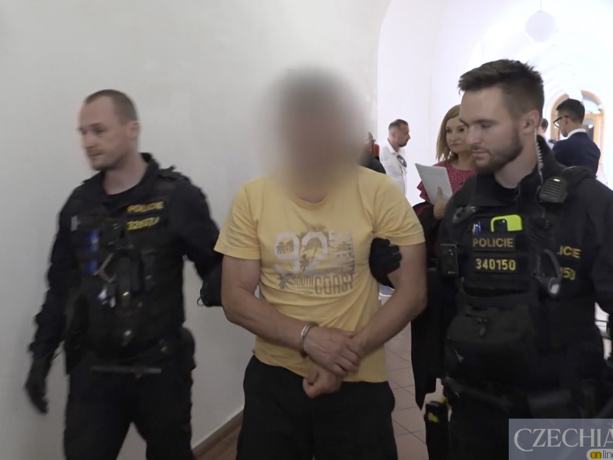 Поліцейські ведуть затриманого чоловіка в кайданках коридором.