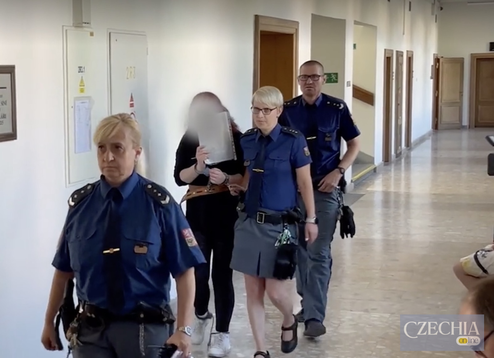 Обвинувачену під конвоєм ведуть коридором будівлі суду в Чехії